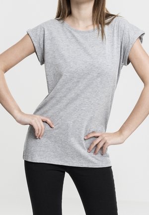 Szary t-shirt z krótkim rękawem z miękkiego materiału, o luźnym kroju i podwiniętych mankietach, w połączeniu z czarnymi dopasowanymi spodniami.