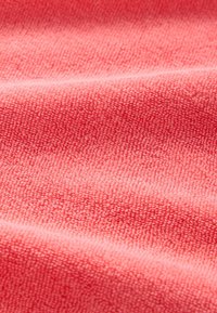 Korallfärgad mikrofiber med en mjuk, strukturerad yta, med fina, upphöjda fibrer och subtila vågmönster.