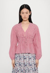 Rot-weiße gestreifte Bluse mit tiefem V-Ausschnitt, elastischem Bund und langen Puffärmel, kombiniert mit einem Blumenkleid. Mischmaterial aus Baumwolle.