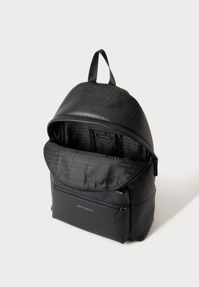 Sac à dos noir Armani Exchange avec des empiècements à motifs, une poignée supérieure, une poche avant zippée et un compartiment principal ouvert laissant voir la doublure siglée.