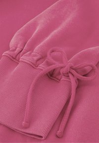 Fuchsia sweatshirt detail met ribbelmanchetten met elastische gather en bijpassende koord voor verstelbaarheid. Zachte textuur en naadloos ontwerp.