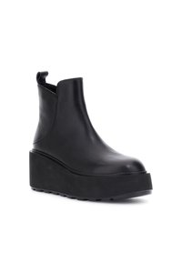 Stivaletti neri in pelle con punta arrotondata, pannelli laterali elastici e suola piatta spessa. Texture liscia con una leggera lucentezza.