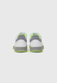 Zapatillas blancas y grises con acentos en verde neón. Presentan una parte superior texturizada y un cuello acolchado, con una suela de goma reforzada para mayor durabilidad.