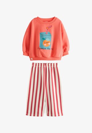 Coral sweatshirt with cartoon orange juice box and "Squeeze the day" text, paired with white and coral vertical striped cropped pants.