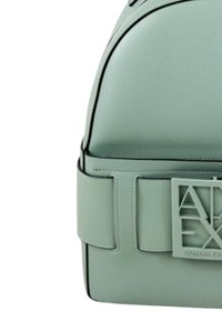 Zaino in ecopelle verde chiaro con parte superiore arrotondata, piping nero e un evidente dettaglio del logo in rilievo sul fronte.