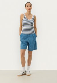Striped tank top in navy and white, paired with lightweight blue shorts. Sneakers with black stripes and white ankle socks complete the outfit.