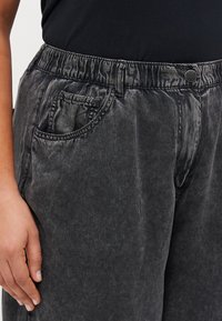 Μαύρο τζιν παντελόνι με λάστιχο στη μέση, μπροστινές τσέπες και λεία υφή, διαθέτει ελαφριά γυαλάδα και casual γραμμή.