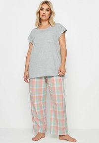 Grijze T-shirt met korte mouwen en een zak, gecombineerd met pastelkleurige geruite pyjamabroek met roze, blauwe, groene en gele vierkanten.