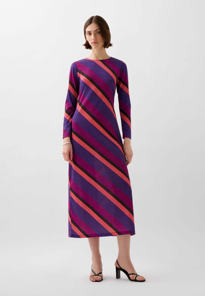 Pitkähihainen violetti mekko, jossa on vinoraitoja vaaleanpunaisena ja mustana. Pehmeä kangas, suora malli ja nilkkapituinen muotoilu. Mustat korot käytössä.
