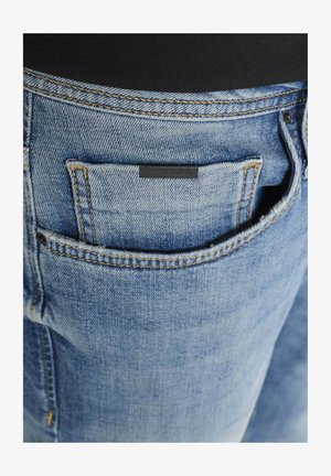 Lichtblauwe denim jeans met een licht vervaagde afwerking, voorzien van een klein zwart label in de achterzak en contrasterende stiksels.