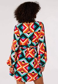 Mehrfarbiges geometrisches Kleid mit langen Ärmeln, tailliertem Bund und einem Rückenausschnitt in Form eines Schlüssellochs. Hergestellt aus einem glatten, leichten Stoff.