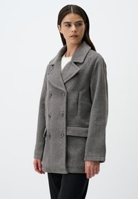 Cappotto in lana grigia con design doppiopetto, colletto con i lembi, grandi bottoni e tasche laterali, caratterizzato da una vestibilità rilassata e un tessuto texture.