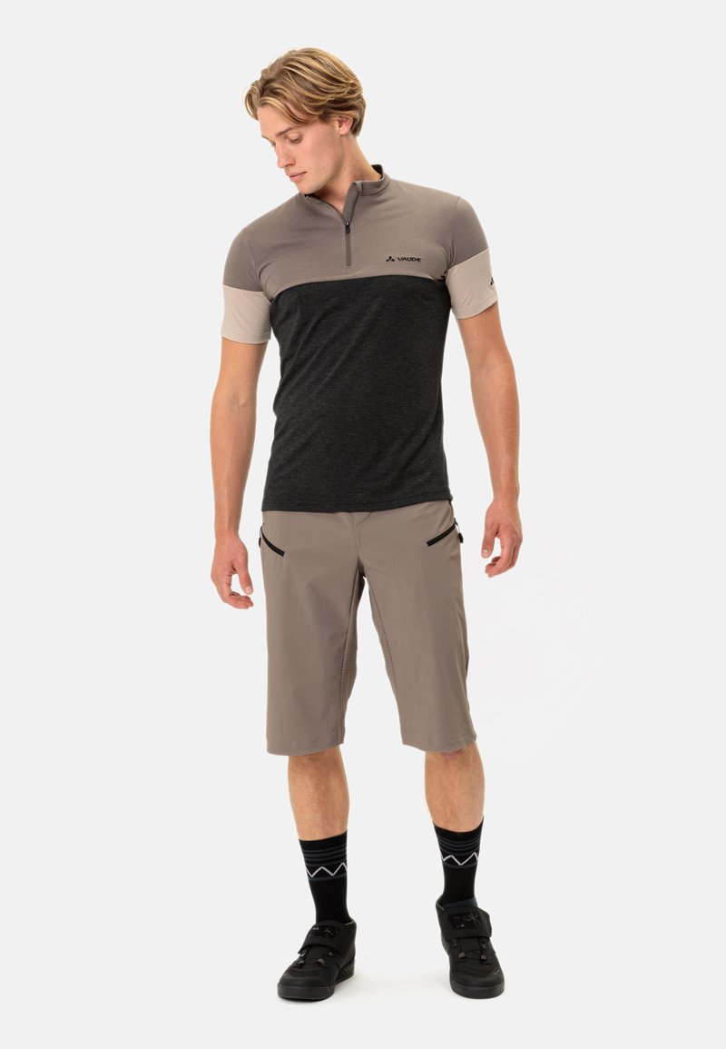 Kurzarm-Polo mit Reißverschluss in Grau und Dunkelgrau, kombiniert mit hellbraunen Shorts mit Reißverschlusstaschen. Strukturierter Stoff mit Vaude-Logo.
