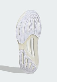 Semelle de sneaker blanche en caoutchouc texturé, dotée de rainures et de découpes pour la flexibilité et l'adhérence. Design minimaliste avec une finition lisse.