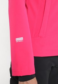 Manica di giacca softshell color rosa acceso, con superficie testurizzata e un'etichetta che recita "ICETECH SOFTSHELL." Design pulito con accenti minimali.