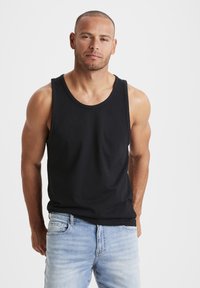 Black sleeveless tank top made of smooth fabric, featuring a round neckline and a relaxed fit, paired with light blue denim jeans.
