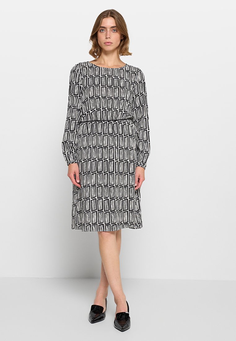 Vestido de estampado en blanco y negro con mangas largas, escote redondo y cintura elástica. De longitud media, con corte recto y textura de tela suave.