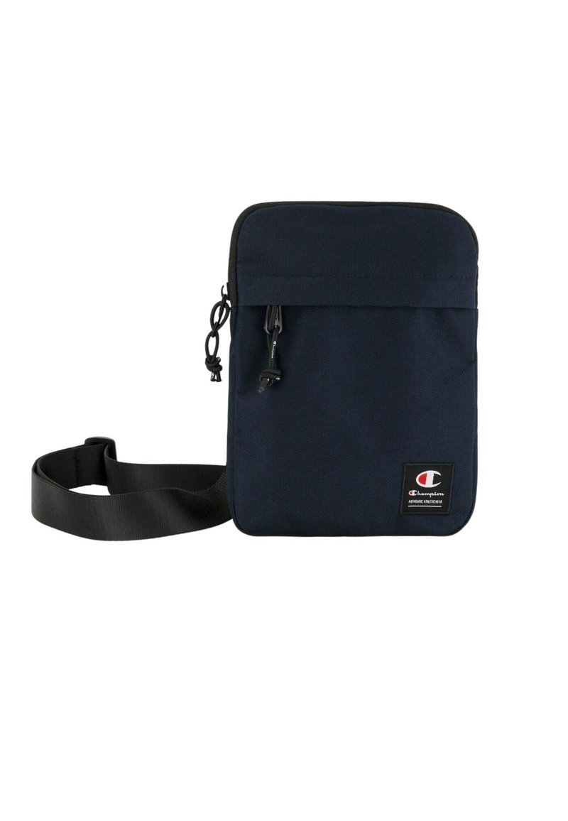 Borsa a tracolla in tessuto blu navy con design piatto, chiusura con zip e tracolla regolabile. Presenta un patch con logo sulla parte frontale.