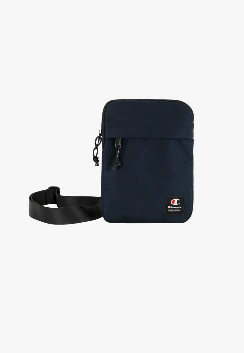 Borsa a tracolla in tessuto blu navy con design piatto, chiusura con zip e tracolla regolabile. Presenta un patch con logo sulla parte frontale.