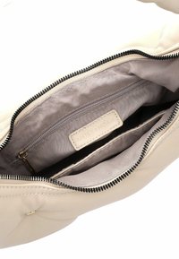 Borsa a mano in pelle beige con chiusura a zip, caratterizzata da una morbida trama trapuntata e due scomparti interni con una tasca con zip e etichetta logo.