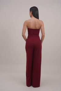 Burgundy strapless jumpsuit with a fitted bodice and wide-leg pants, featuring a concealed back zipper and smooth, stretchy fabric.
