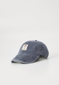 Blue denim cap with curved brim and stitched detailing. Features a square patch depicting a figure with wings and text "ARWING SOCIETY."