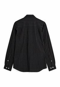 Chemise noire à manches longues avec motif à grille blanche, poignets boutonnés et col, vue de dos sur fond blanc.