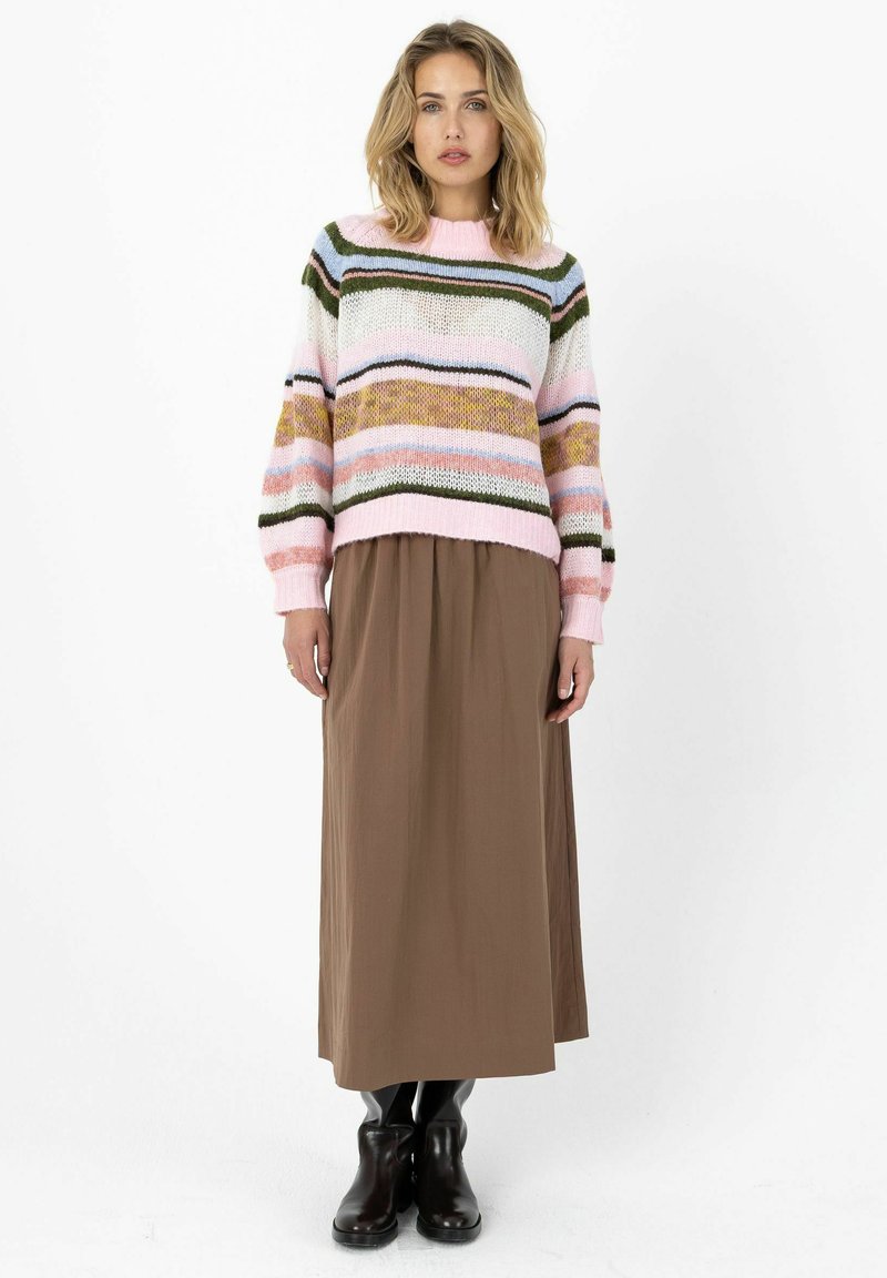 Pull en maille avec rayures multicolores, comprenant du rose, du vert et du bleu, associé à une jupe longue marron et des bottines noires.