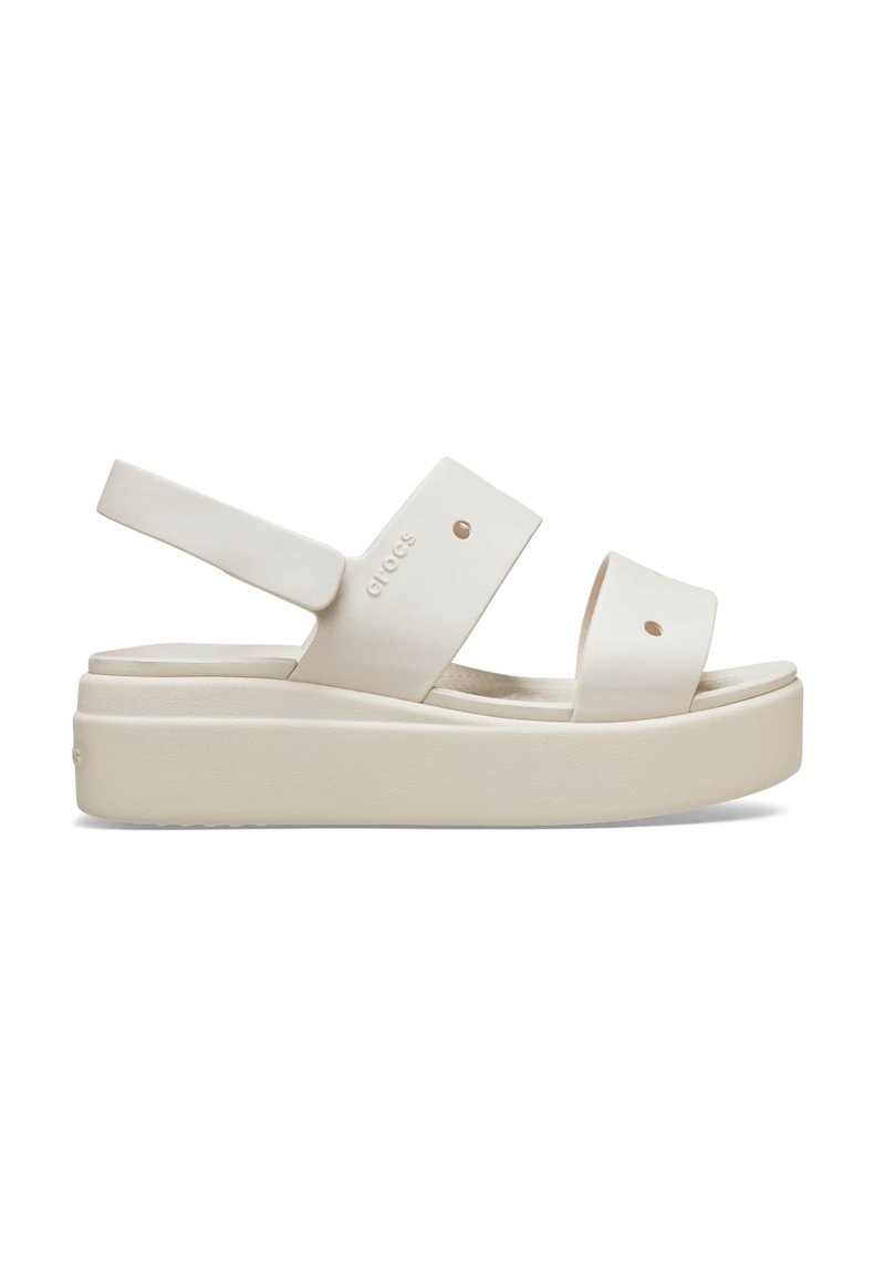 White platform sandals with wide straps, made of smooth material, featuring adjustable back strap and pronounced sole. Minimalistic design.