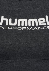Donkergrijze stof met witte vette tekst "hummel" en kleinere tekst "PERFORMANCE" erop gedrukt.