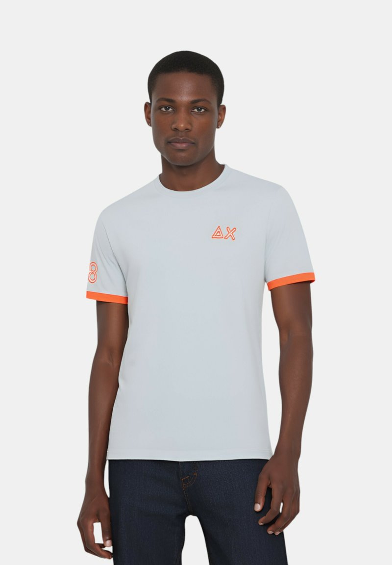T-shirt grigio chiaro a maniche corte con dettagli arancioni sulle maniche. Presenta un logo stampato sul petto. Realizzato in un tessuto liscio e elasticizzato.