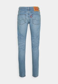 Jean en denim bleu clair avec jambes droites, deux poches arrière, une étiquette rouge Levi's et un patch logo Levi Strauss en cuir marron sur la ceinture.
