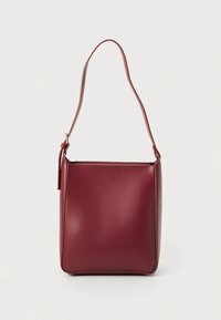 Τετράγωνη χιαστί τσάντα μπορντό από λείο συνθετικό υλικό, με έναν μονό ιμάντα ώμου και διακριτικό, μίνιμαλ σχεδιασμό.