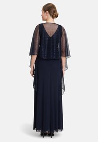 Lungo abito blu navy con maniche svasate trasparenti e scollatura profonda a V sul retro. Tessuto morbido con una leggera lucentezza, design lungo fino al pavimento e silhouette a strati.