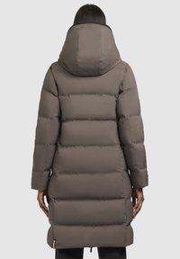 Pikk, kohev hall sulejope, millel on suur, kinnitatud kapuuts, õmblusdetailid ja reguleeritav äär. Sile tekstuur ja mati viimistlus.