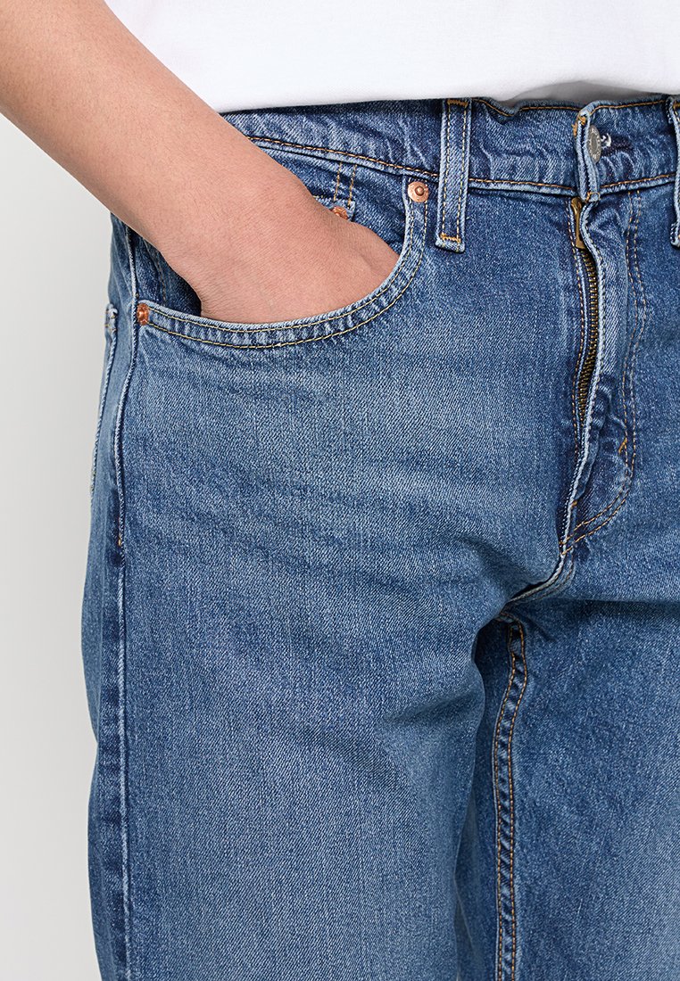 Hellblau gefärbte Jeans aus Denim mit einem klassischen Fünf-Taschen-Design, Metallbeschlägen und subtiler Used-Optik entlang der Beine.