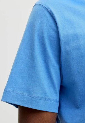 T-shirt di cotone azzurro chiaro con collo rotondo, maniche corte e una texture liscia. Presenta orli cuciti con cura e una vestibilità rilassata.