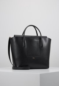 Svart läder tote väska med dubbla handtag och ett avtagbart axelband. Har en texturerad yta och en framficka med en gyllene emblem.