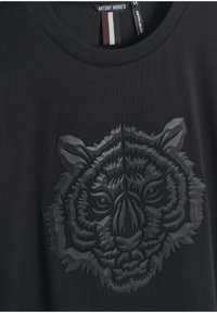 Crna pamučna majica s podignutom, monokromatskom tigrovom grafikom na prednjoj strani. Okrugli izrez s klasičnim krojem.