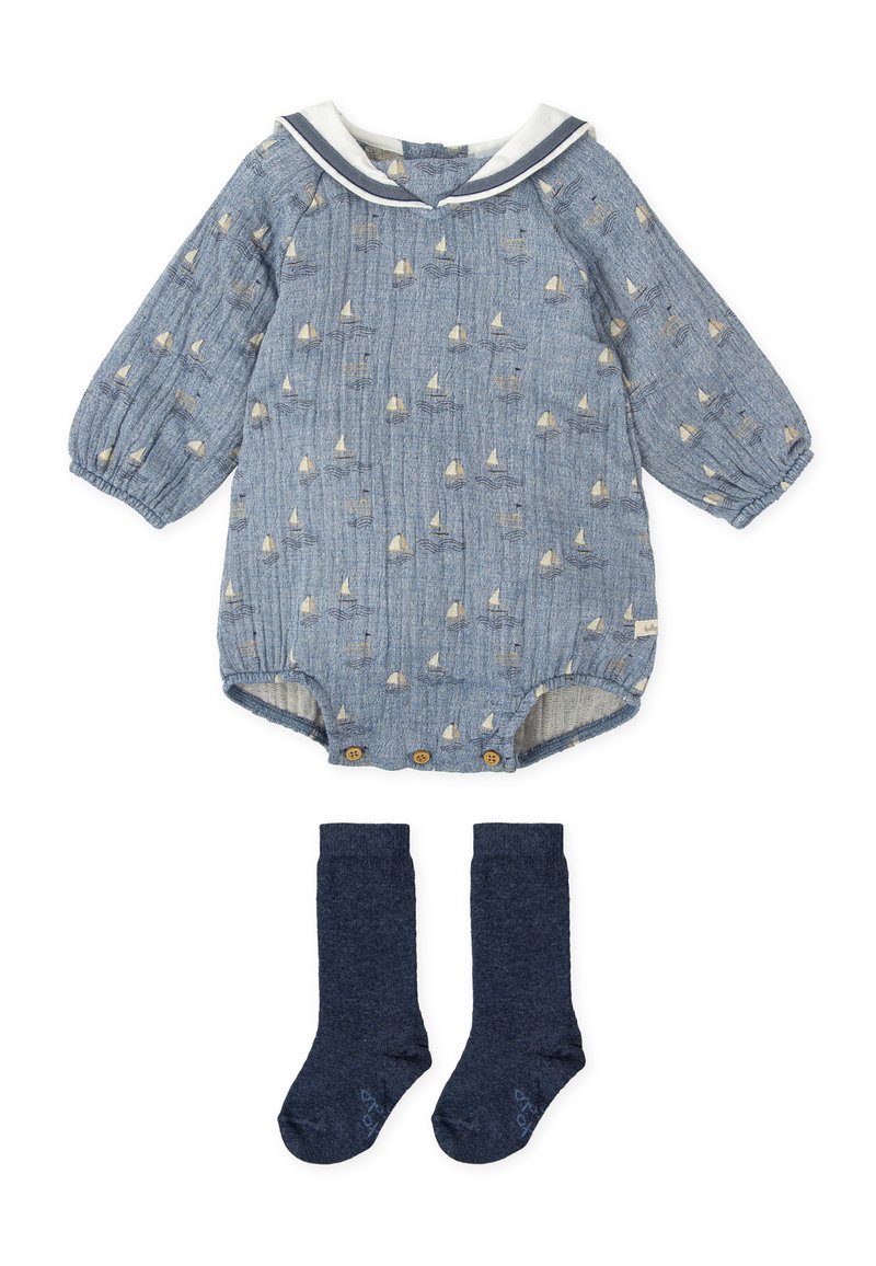Mono de bebé de manga larga azul con patrón de barco de vela, cuello de marinero blanco, botones de madera y calcetas altas de rodilla de color azul marino.