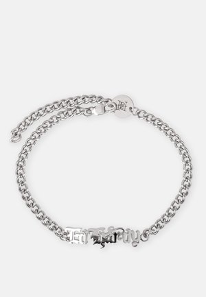 Bracelet en chaîne argentée avec un design à double couche et un centre décoratif en texte, sécurisé par un fermoir et une étiquette gravée.