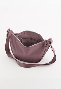 Lilla nylon skuldertaske med en glat tekstur, lynlåslomme i hovedrummet og justerbar stofrem. Indeholder en indvendig lomme.