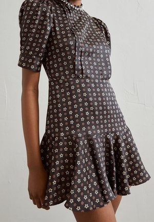 Robe noire avec manches bouffantes courtes et ourlet évasé, ornée d'un motif d'étoiles et de cercles blancs et rouille.