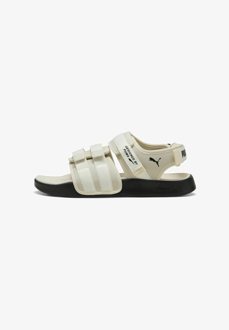 Sandală albă cu barete Velcro ajustabile, vârf rotund și talpă neagră. Are un logo pe toc și un superior texturat pentru aderență.