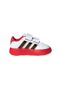 Dziecięce białe sneakersy z czerwoną podeszwą i wyściółką, czarno-żółtym paskowanym wzorem i dwoma białymi paskami na rzep.