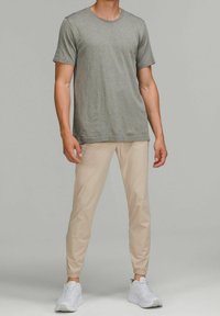 Grå mönstrad t-shirt med kort ärm i kombination med beige smala byxor. Vita sneakers fulländar outfiten, med elastiska manschetter.