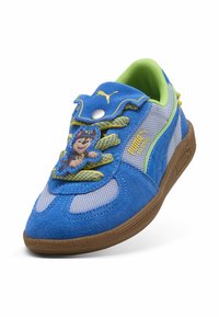 Baskets Puma bleues et grises avec lacets jaunes, doublure intérieure verte, semelle marron et décoration d’un personnage de Paw Patrol sur la languette.