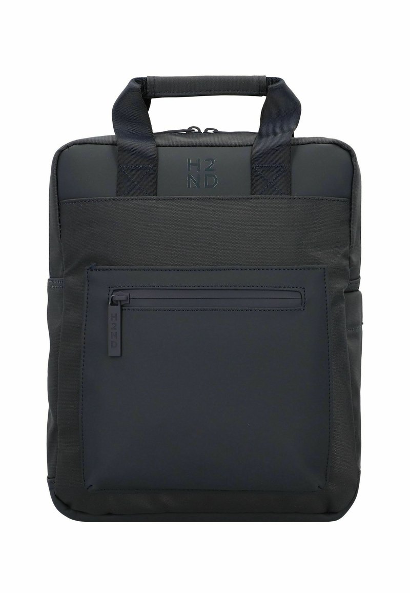 Mochila de tela negra con asas superiores dobles, bolsillo frontal con cremallera y logo en relieve. Textura suave y diseño cuadrado minimalista.