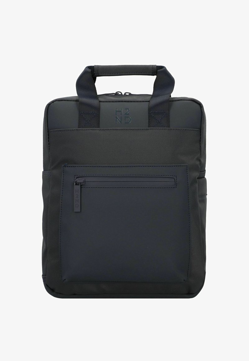 Mochila de tela negra con asas superiores dobles, bolsillo frontal con cremallera y logo en relieve. Textura suave y diseño cuadrado minimalista.