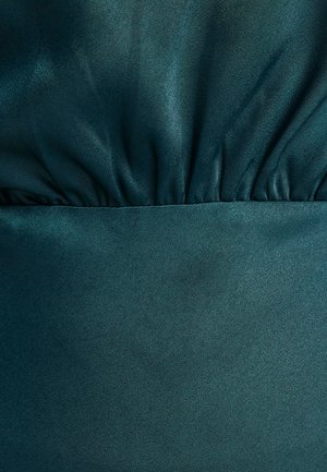 Teal saten tkanina sa glatkom teksturom. Nabran detalj na vrhu i čvrsti panel na dnu stvaraju vizualni interes i dubinu.